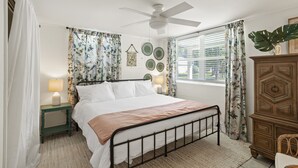 A bedroom with a bed, a nightstand, a dresser, and a window with curtains. - Downtown Cottage! Walk/Cart Everywhere, 2 King Beds (Ocean Springs)