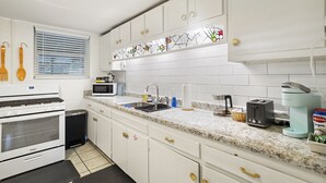 A kitchen with white cabinets, a microwave, a toaster, and a coffee maker. - Downtown Cottage! Walk/Cart Everywhere, 2 King Beds (Ocean Springs)