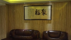 A room with two leather chairs and a framed calligraphy piece on the wall. - Jufu Hotel (Enping)