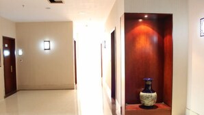 Pasillo de hotel con piso pulido, una recepción de madera y un jarrón en exhibición.