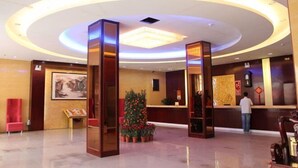 Un vestíbulo de hotel con una recepción, un árbol de Navidad y un cuadro grande en la pared.