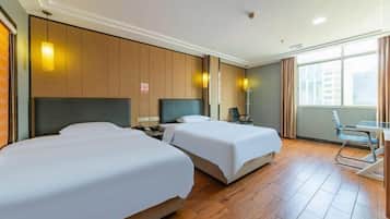 Habitación de hotel con dos camas, un escritorio, una silla y una ventana con cortinas.