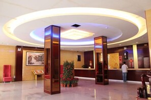 Un vestíbulo de hotel con mostrador de recepción, un árbol de Navidad y un cuadro grande en la pared.