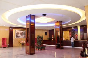 A hotel lobby with a reception desk, a Christmas tree, and a large painting on the wall.