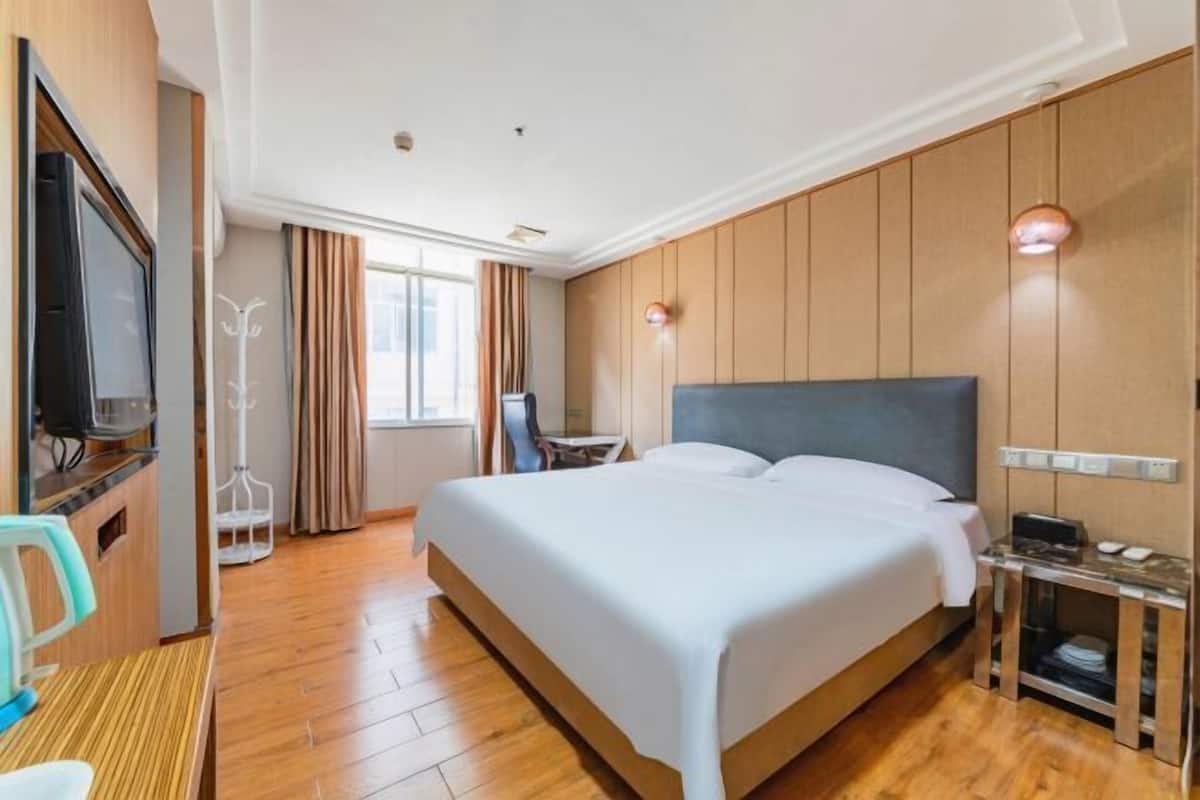 Una habitación de hotel con cama, televisión, escritorio y silla.