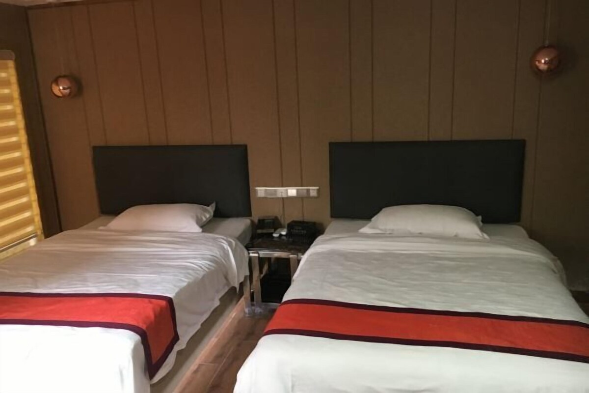 A hotel room with two beds, each with white bedding and a red accent.
