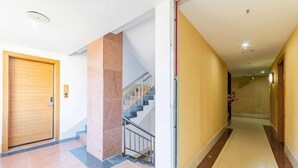 Un pasillo de hotel con una puerta de madera, un pilar de mármol y una escalera.