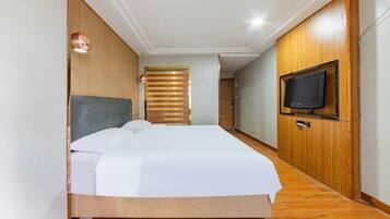 Un dormitorio con cama, paneles de madera, televisor y luz de techo.