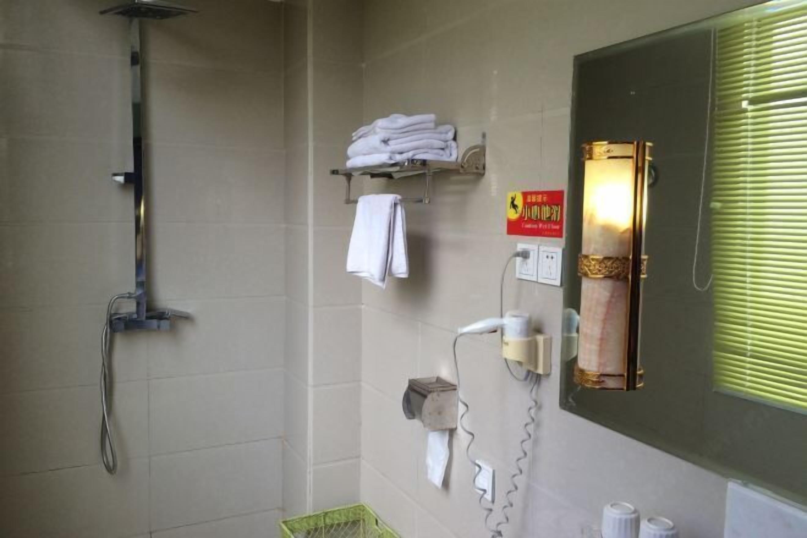 A bathroom with a shower, towel rack, and a mirror with a sign.