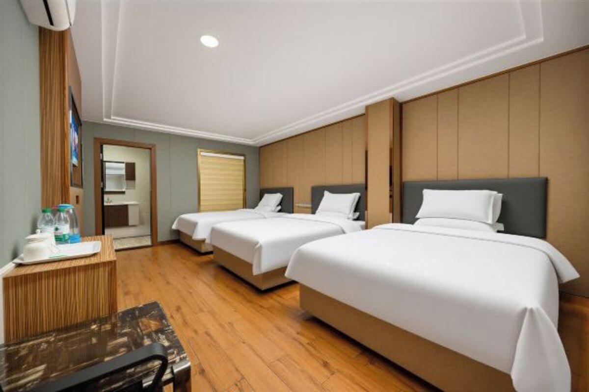 A hotel room with two beds, a wooden desk, and a mirror.