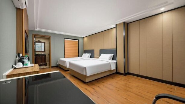 Habitación de hotel con dos camas, un escritorio, un espejo y una puerta corredera.