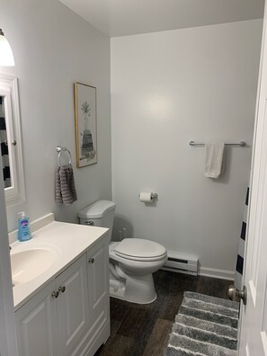Et badeværelse med toilet, vask og bruseområde.
