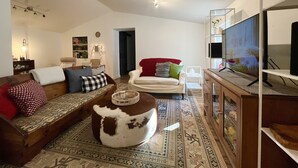 Una sala de estar con sofá, reposapiés y televisor.