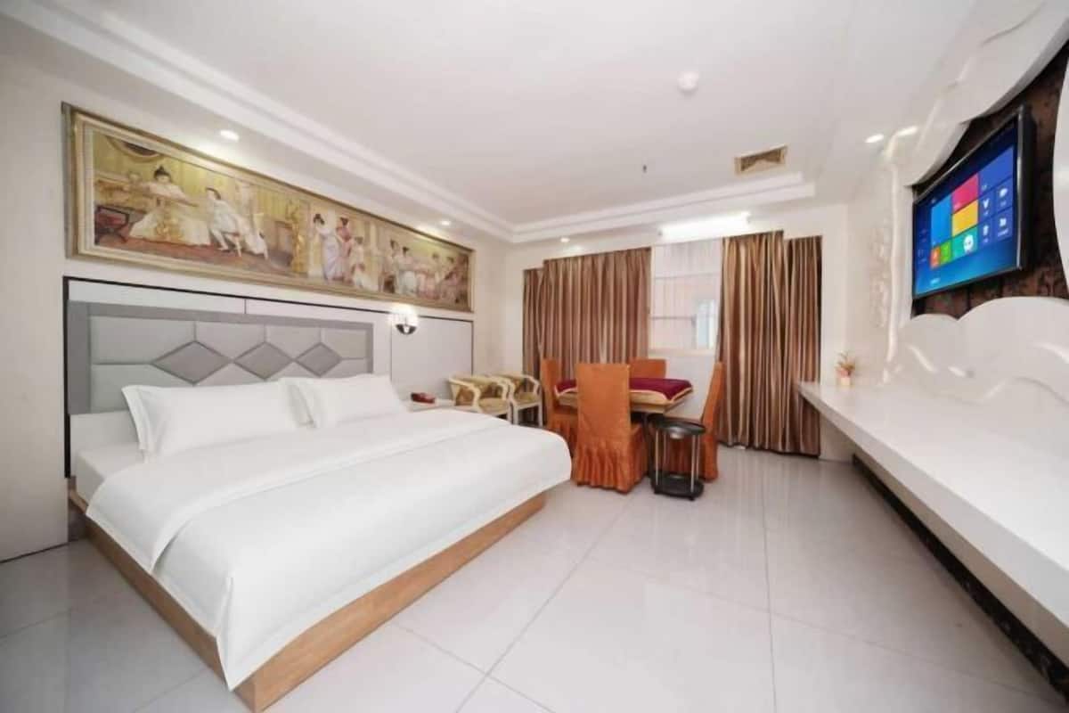 Una habitación de hotel con cama, escritorio, silla, televisor y un cuadro en la pared.