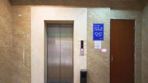 An elevator in a lobby with a marble floor and a wooden door to the right. - Lehao Business Hotel (Foshan Lecong International Convention and Exhibition Center) (Foshan)