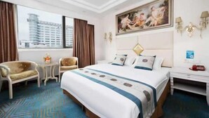 A hotel room with a large bed, a desk, a chair, and a view of a building outside. - Lehao Business Hotel (Foshan Lecong International Convention and Exhibition Center) (Foshan)