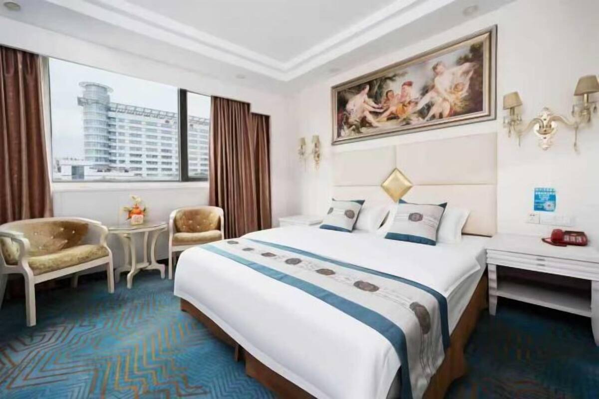 Habitación de hotel con una cama grande, un escritorio, una silla y vista a un edificio.