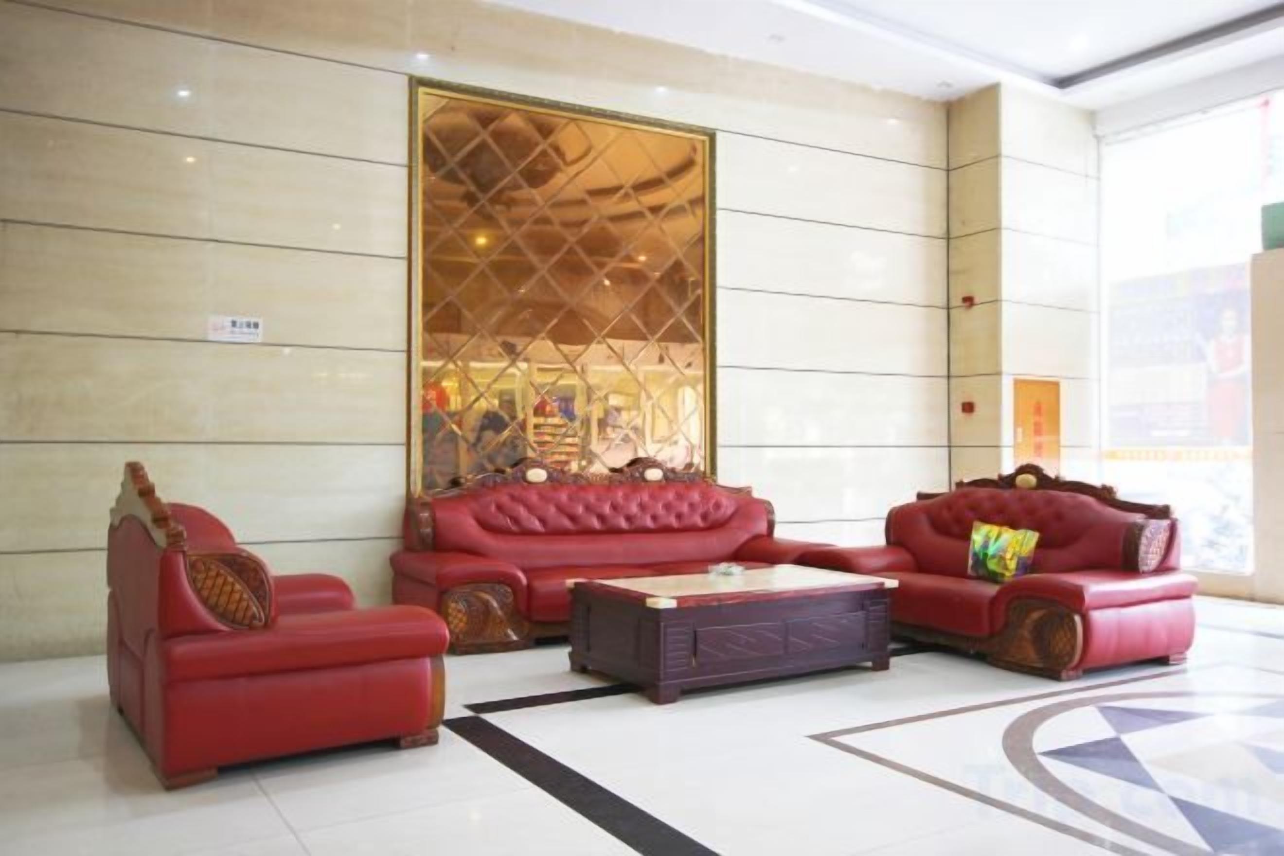 A lobby with a red sofa set, a coffee table, and a patterned wall.