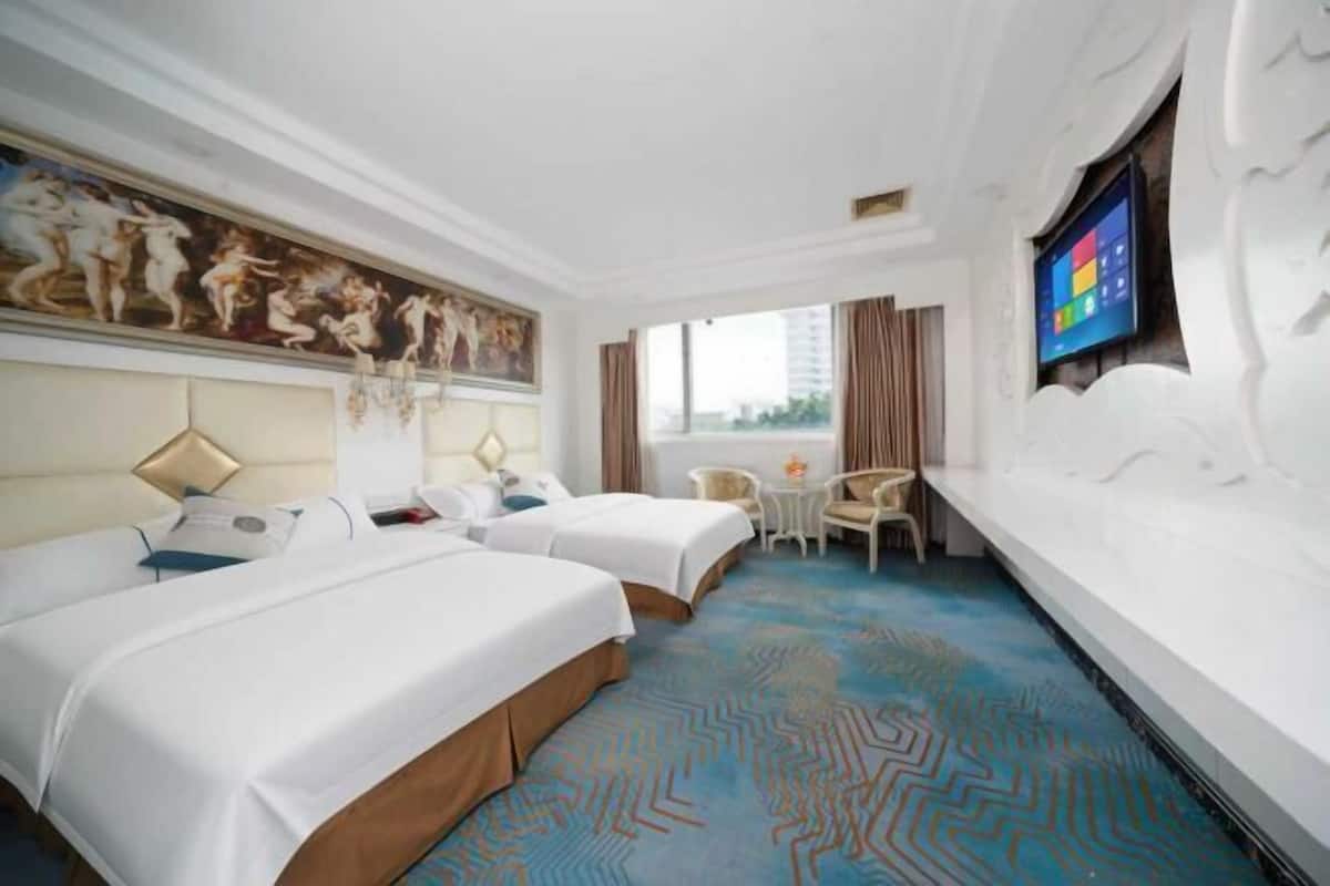 Habitación de hotel con dos camas, un cuadro grande en la pared, un televisor de pantalla plana y vistas a la ciudad.