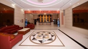 A hotel lobby with a reception desk, red sofas, a patterned floor, and a chandelier. - Lehao Business Hotel (Foshan Lecong International Convention and Exhibition Center) (Foshan)