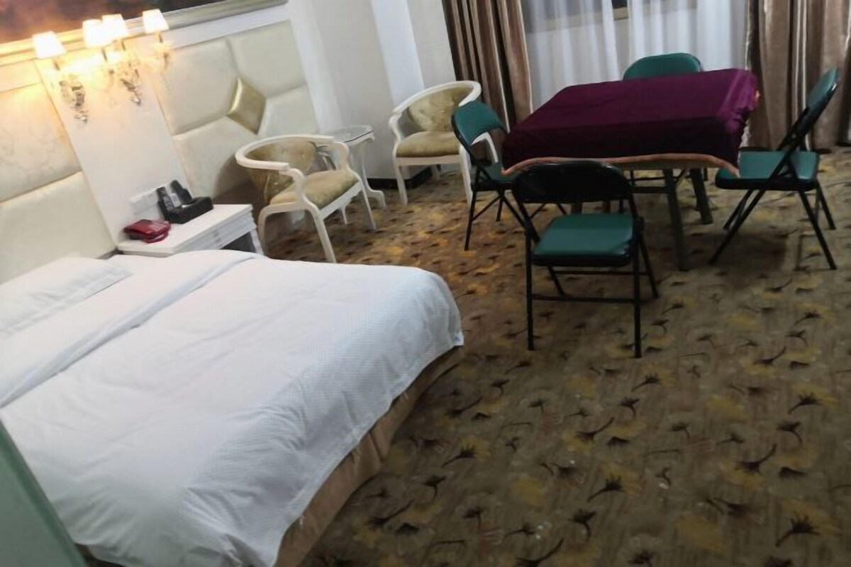 A hotel room with a bed, a small table with a purple tablecloth, and several chairs.