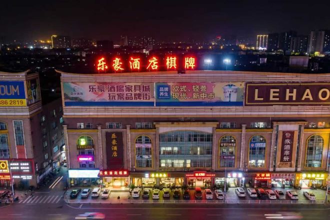 A hotel with a prominent sign, multiple parking spaces, and a cityscape in the background.