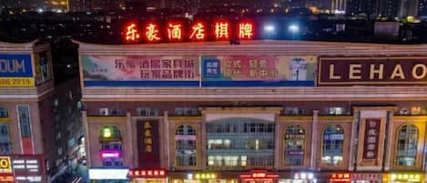 A hotel with a prominent sign, multiple parking spaces, and a cityscape in the background.