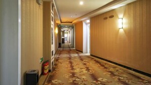 A hotel hallway with a floral carpet, wooden paneling, and wall-mounted lighting. - Lehao Business Hotel (Foshan Lecong International Convention and Exhibition Center) (Foshan)