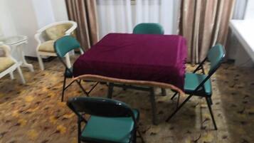 A dining area with a table covered by a maroon tablecloth, surrounded by green chairs.