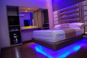 A modern bedroom with a large bed, built-in shelving, and a mirror. - Hotel ByHours Astor (Barranquilla)