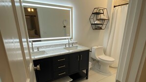 A modern bathroom with a large mirror, a toilet, and a sink.