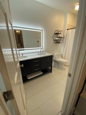 A modern bathroom with a large mirror, a toilet, and a sink.