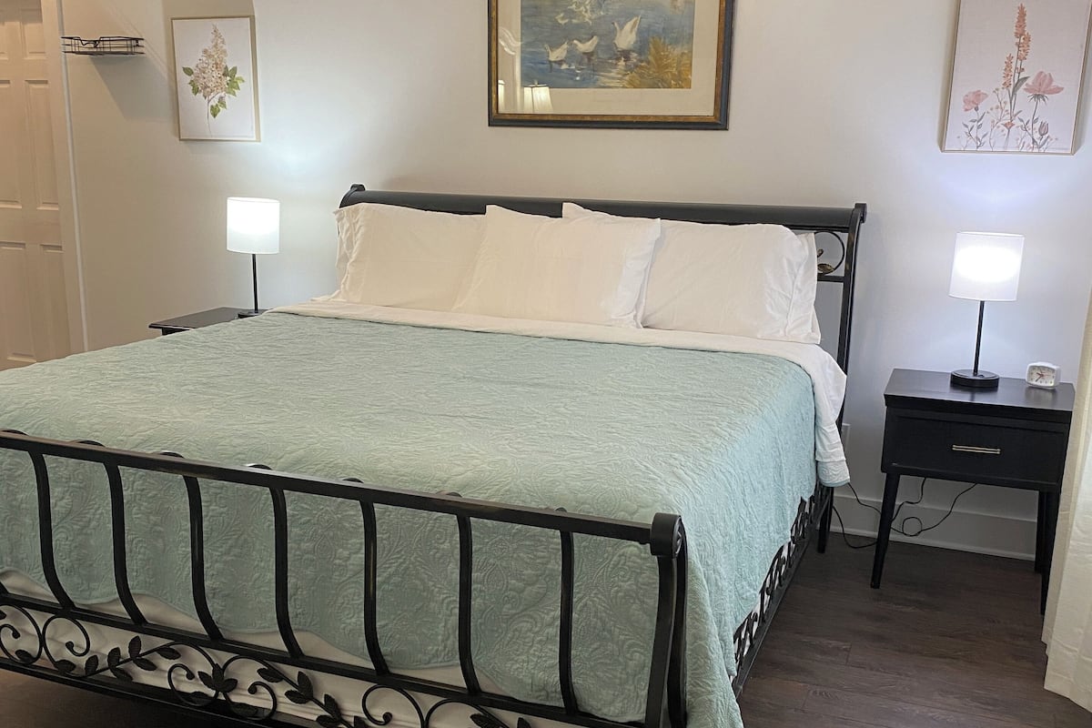 A neatly arranged bedroom with a bed, bedside tables, and a chair.