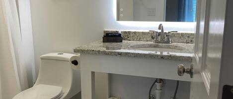 A modern bathroom with a toilet, sink, and mirror.