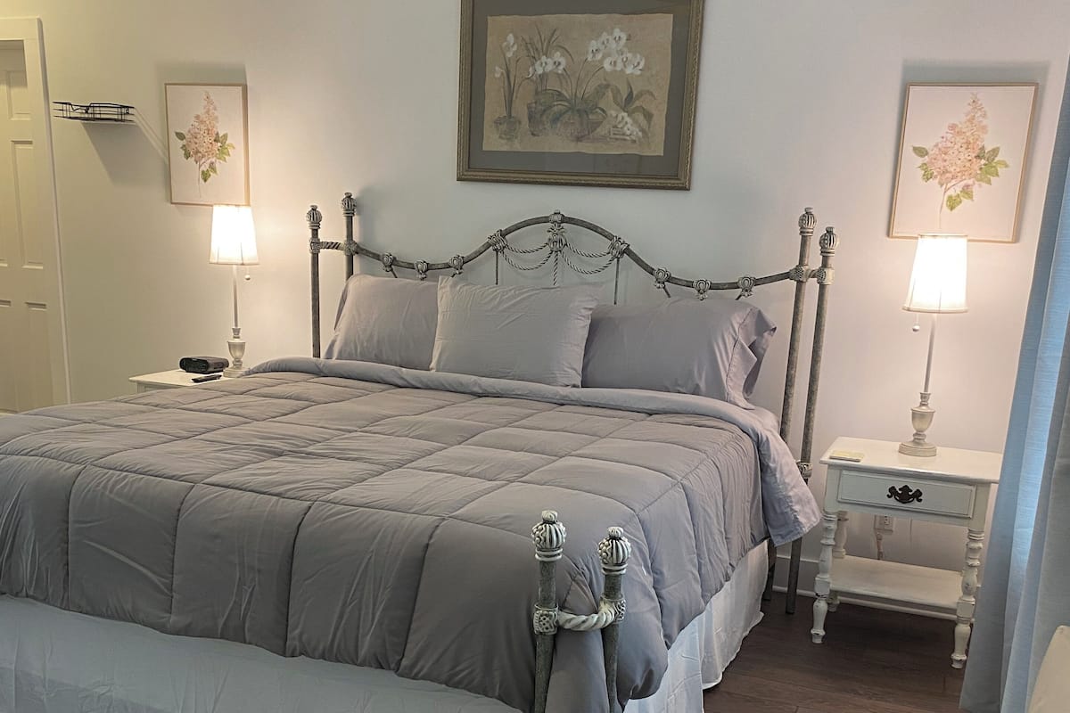 A neatly arranged bedroom with a large bed, two bedside tables, a chair, and a door.
