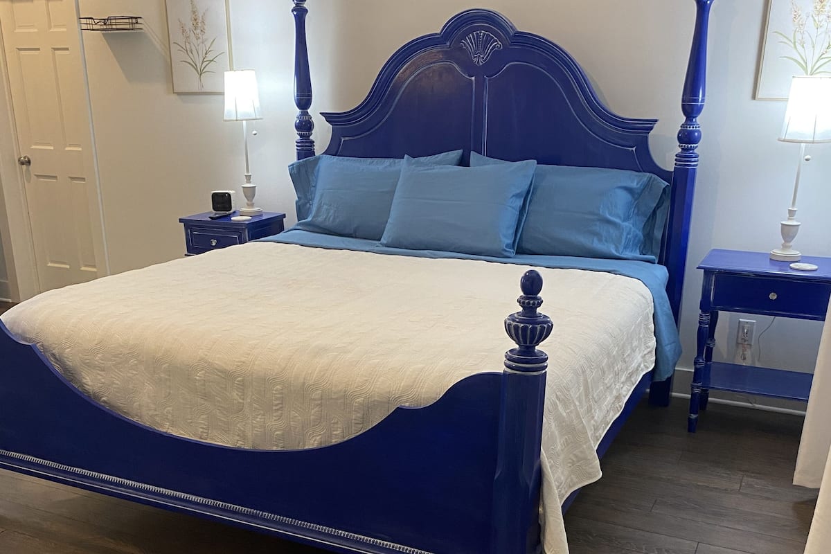 A bedroom with a large bed, two nightstands, a blue headboard, and a patterned rug.
