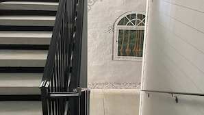 A staircase with a black railing leading to a landing with a small window. - Little Inn on Main (Washington)