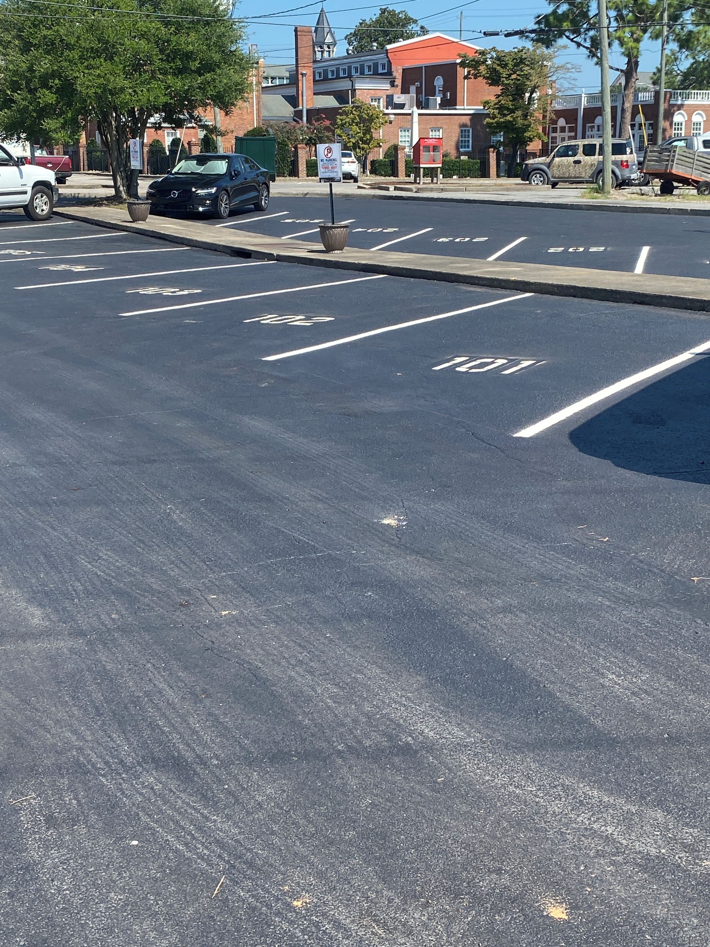 A parking lot with marked spaces and a no parking sign.