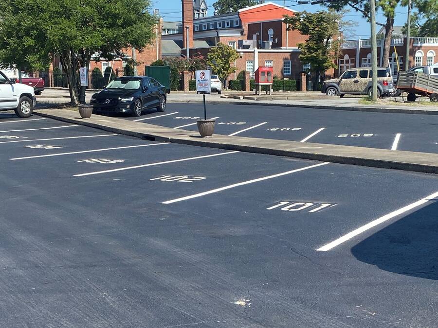 A parking lot with marked spaces and a no parking sign.