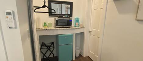 A compact kitchen with a microwave, coffee maker, and a small refrigerator.