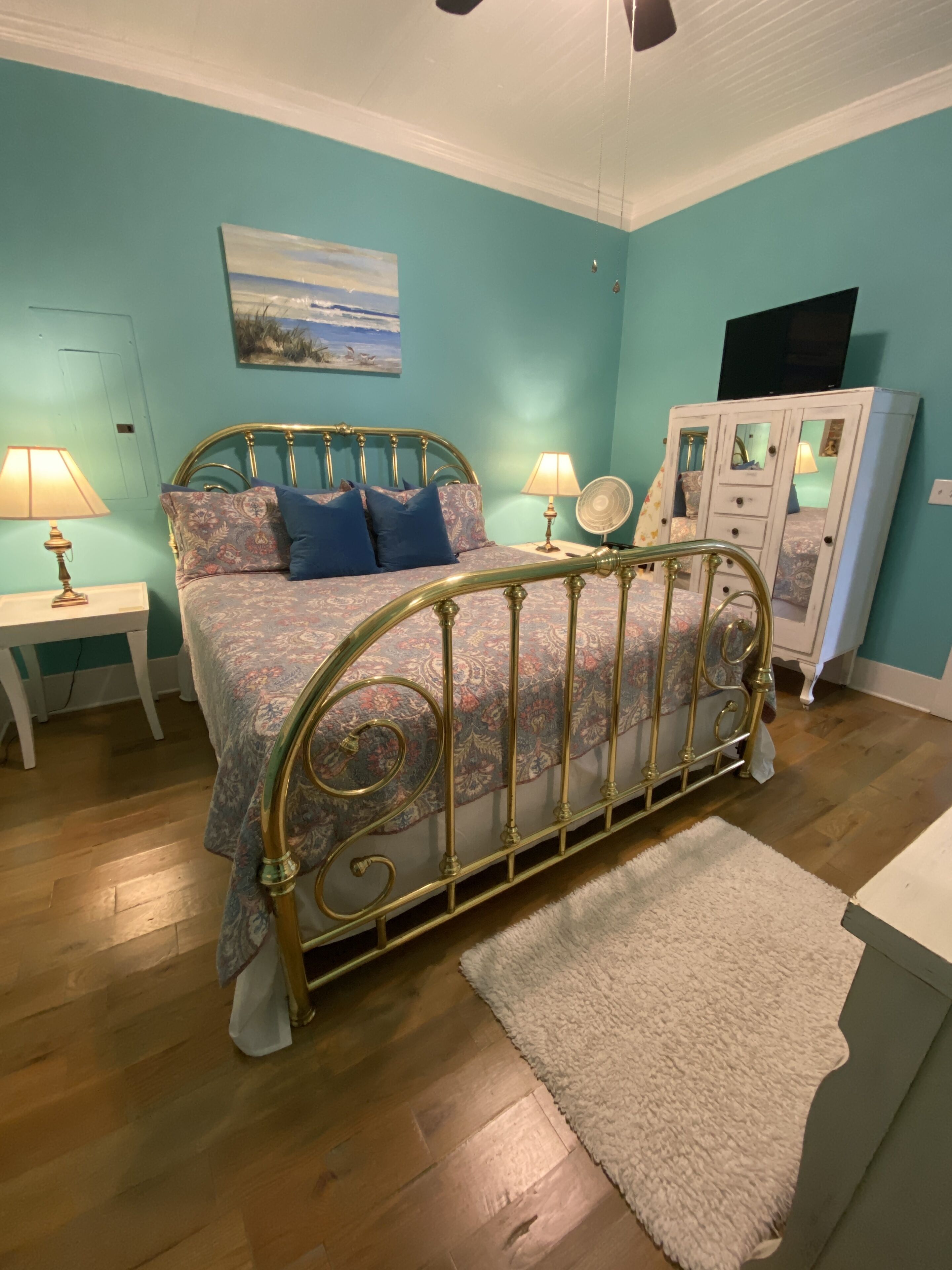 A bedroom with a bed, two bedside tables, a dresser, and a mirror.