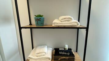 A bathroom with a metal shelf unit holding towels and a small plant.