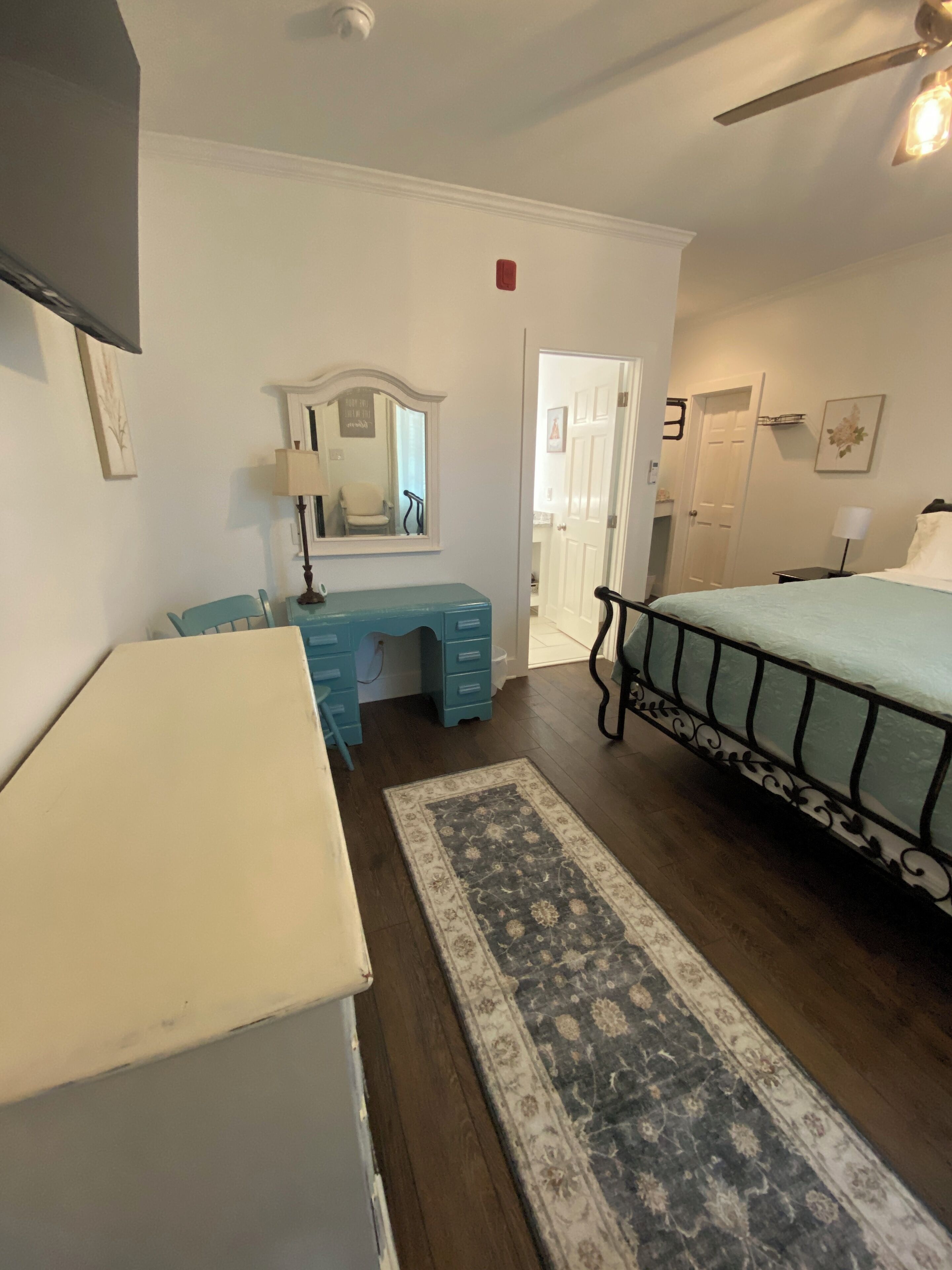 Une chambre à coucher avec un lit, une commode, un bureau et un miroir.