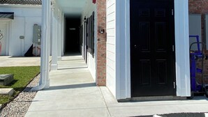 A building with a brick facade, a black door, and a covered walkway leading to a parking area. - Little Inn on Main (Washington)