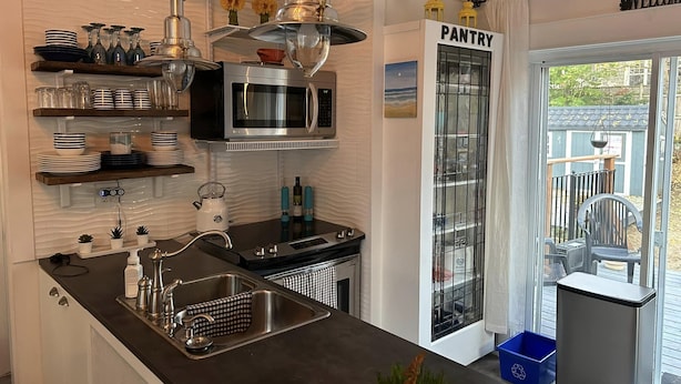 Una cucina moderna con forno a microonde integrato, lavello in acciaio inossidabile e lampade a sospensione.