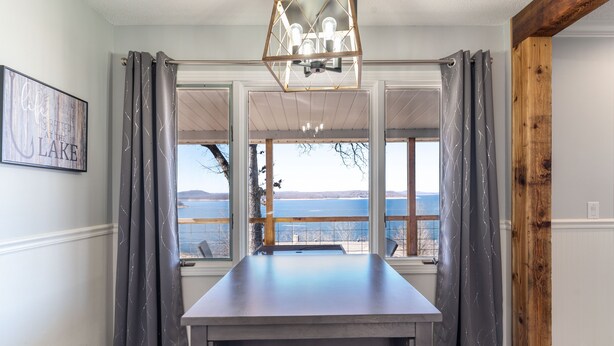 Une pièce avec une table, des rideaux, un lustre et une vue sur un lac.