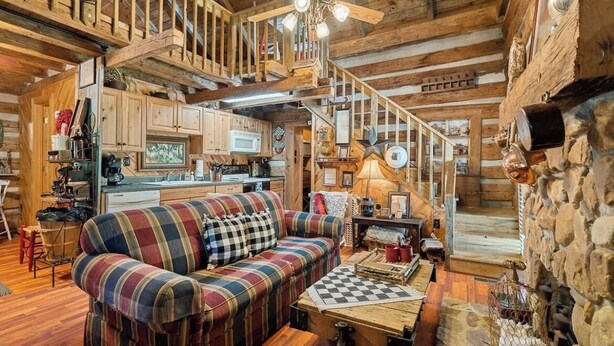 L’intérieur d’un chalet rustique, avec un escalier en bois, un canapé à carreaux et un coin cuisine.