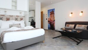 Une chambre d’hôtel moderne avec un grand lit, un canapé, une table basse et un ventilateur de plafond.
