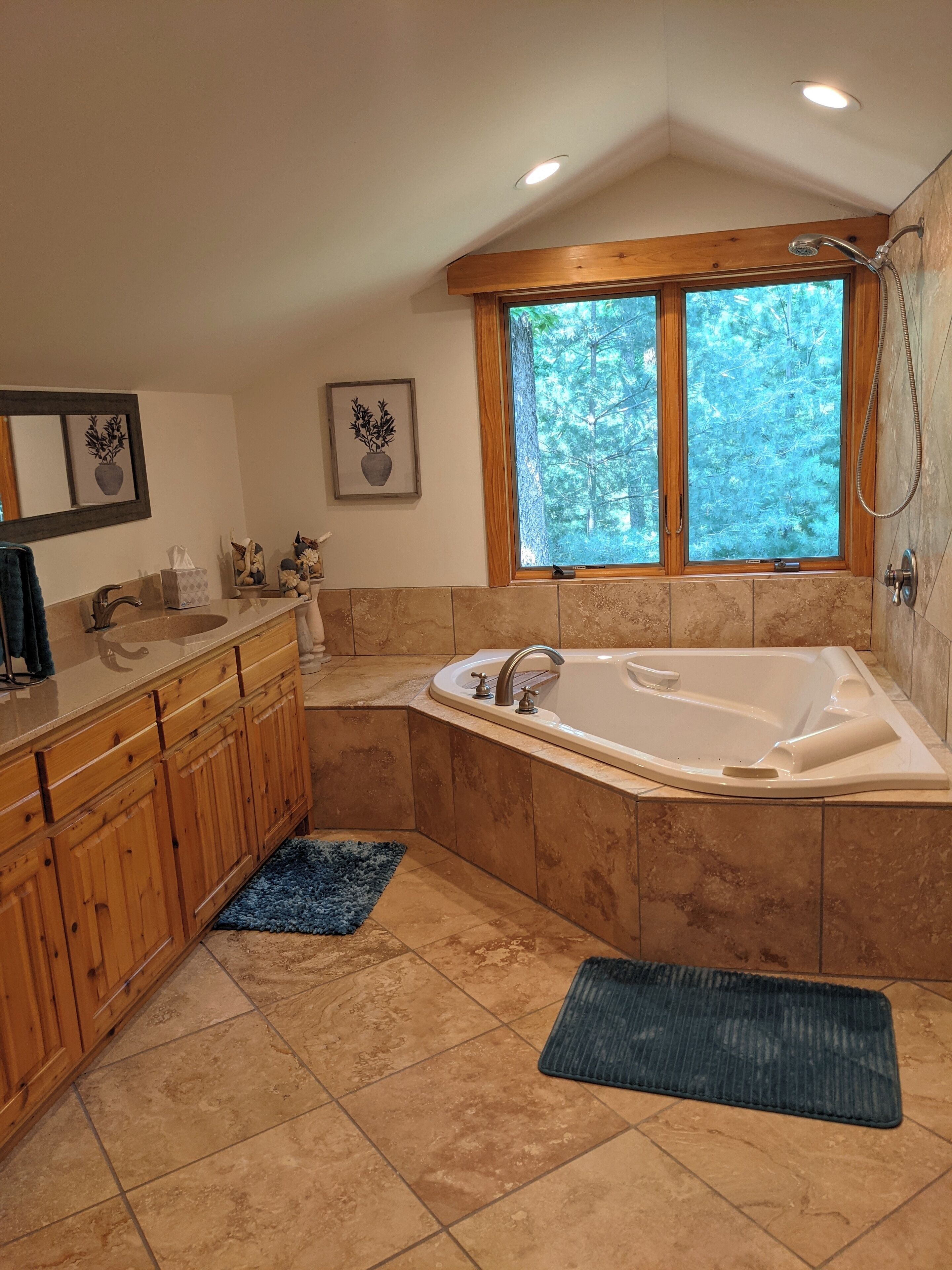 A bathroom with a freestanding bathtub, a sink, and a window with a view of trees.