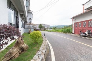 Vista de la calle con un edificio a la izquierda, un scooter estacionado a la derecha y una carretera despejada.
